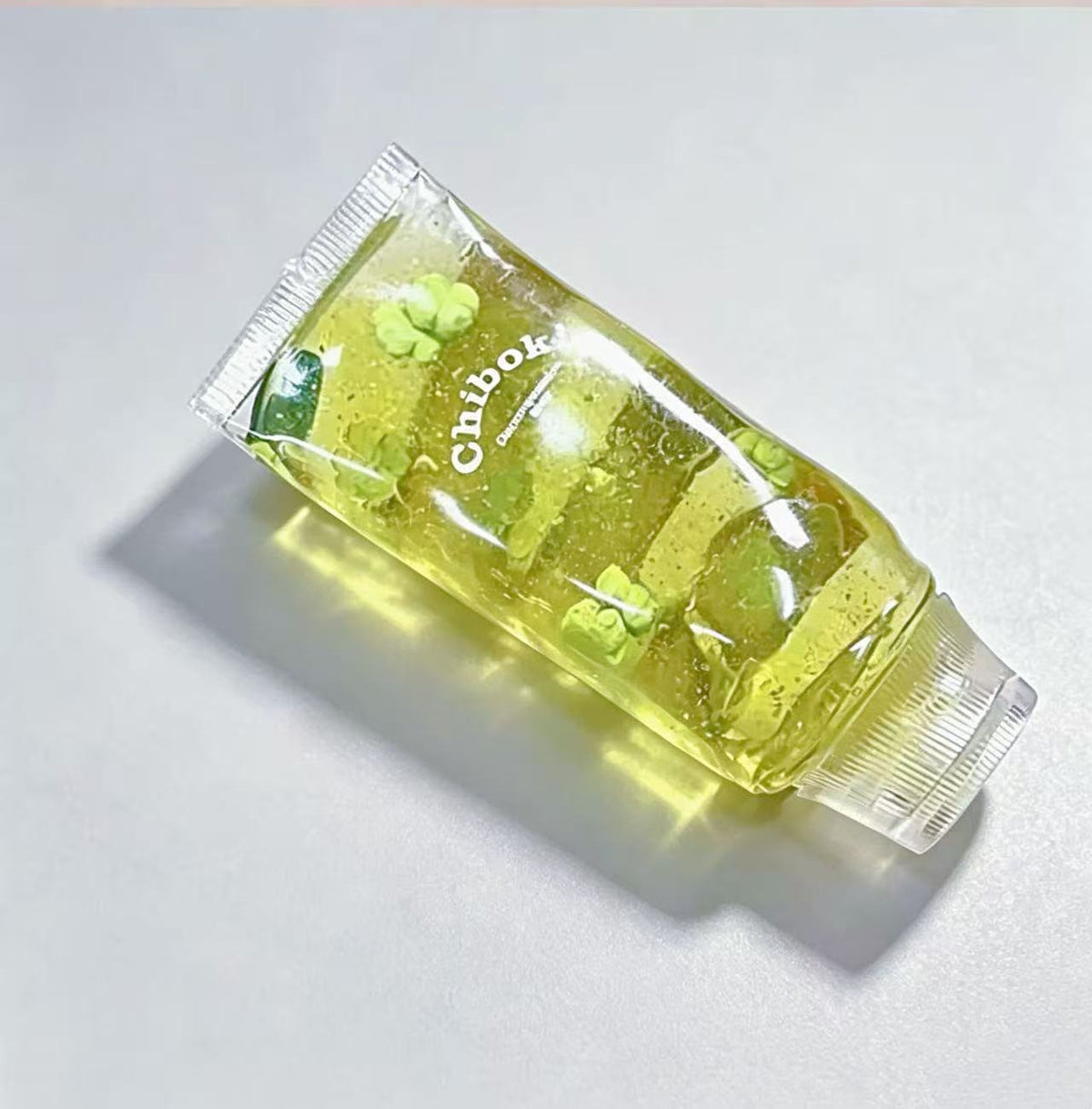 Green squishy toothpaste squeeze toy tube with ridged silver cap
