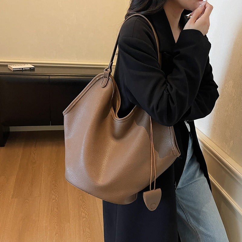 Women’s PU bucket tote bag with lychee-grain texture, light tan, worn on shoulder