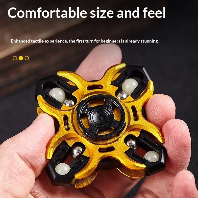 Gold and black fidget spinner held in a hand, showing central bearing and grips