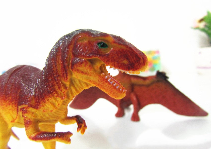 Close-up of a red-orange dinosaur model figure with open mouth and teeth