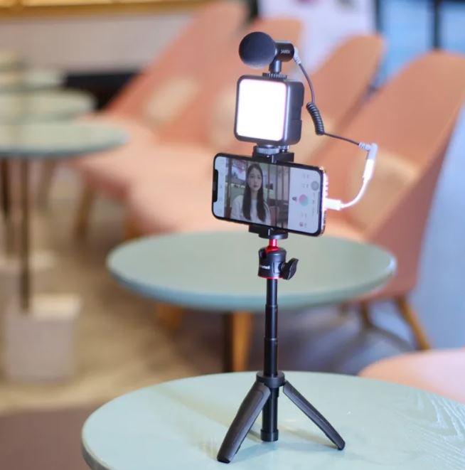 Phone mounted on selfie stick with LED fill light and fold-out tripod legs