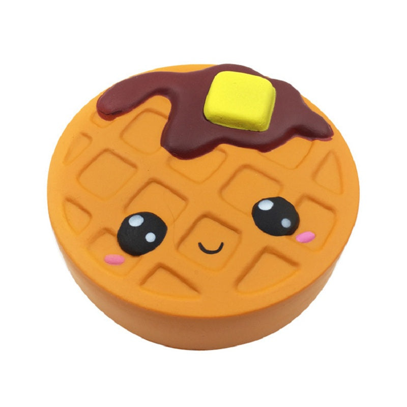 Squishy waffle biscuit plush toy with orange base, dark chocolate patches, smiling face.