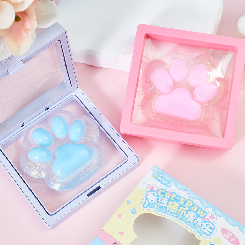 Blue and pink cat-paw squeeze toys in open plastic trays with product boxes