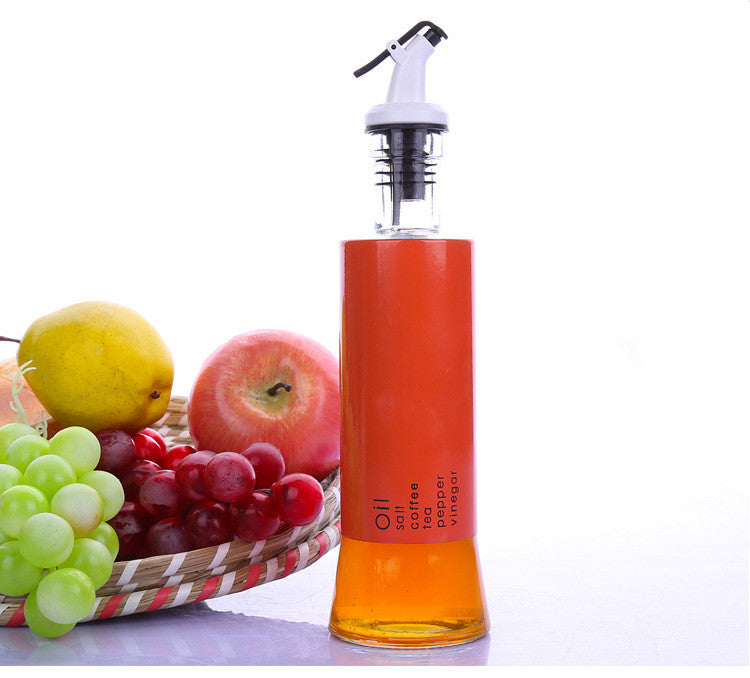Glass oil dispenser bottle with white pump top and orange body holding amber liquid