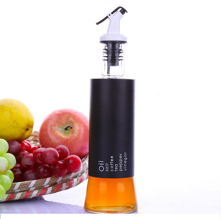 Glass oil dispenser bottle with white pump top, black body and amber liquid