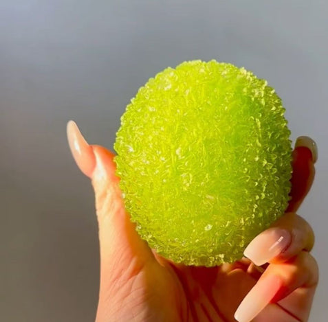 Squishy slow-rise stress relief toy, textured lime-green fruit ball in hand
