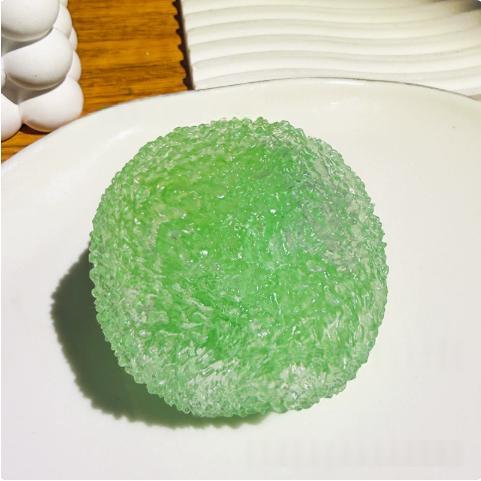 Squishy slow-rise stress relief toy, textured green fruit ball on white plate