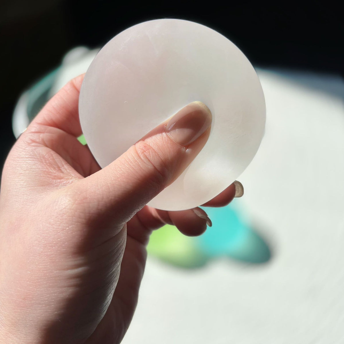 Translucent round squishy candy squeeze toy, pale white, held in hand
