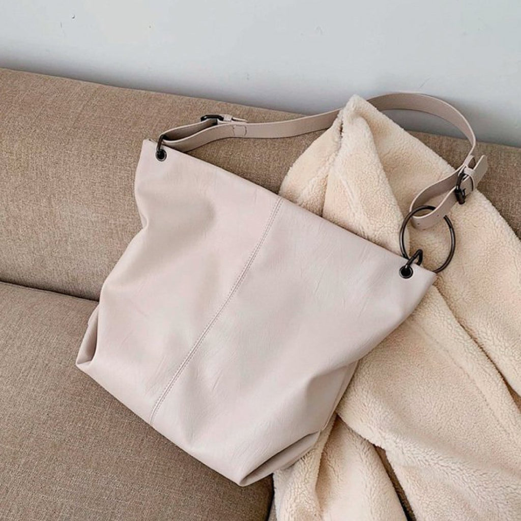 Ivory shoulder bag with top handle, adjustable strap, and ring zipper hardware
