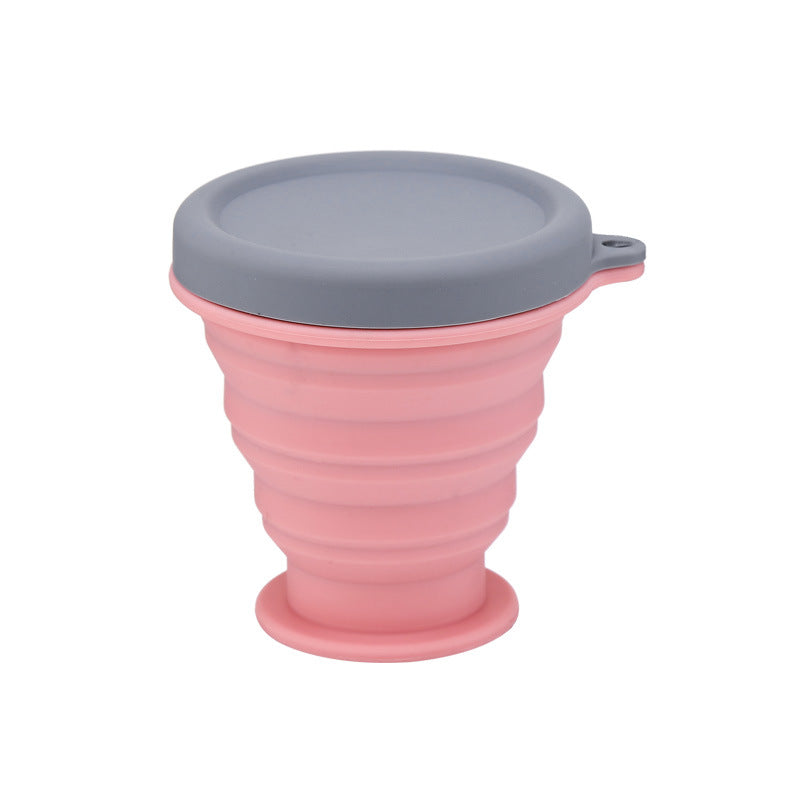 Collapsible silicone travel coffee cup in pink with gray lid and side handle loop