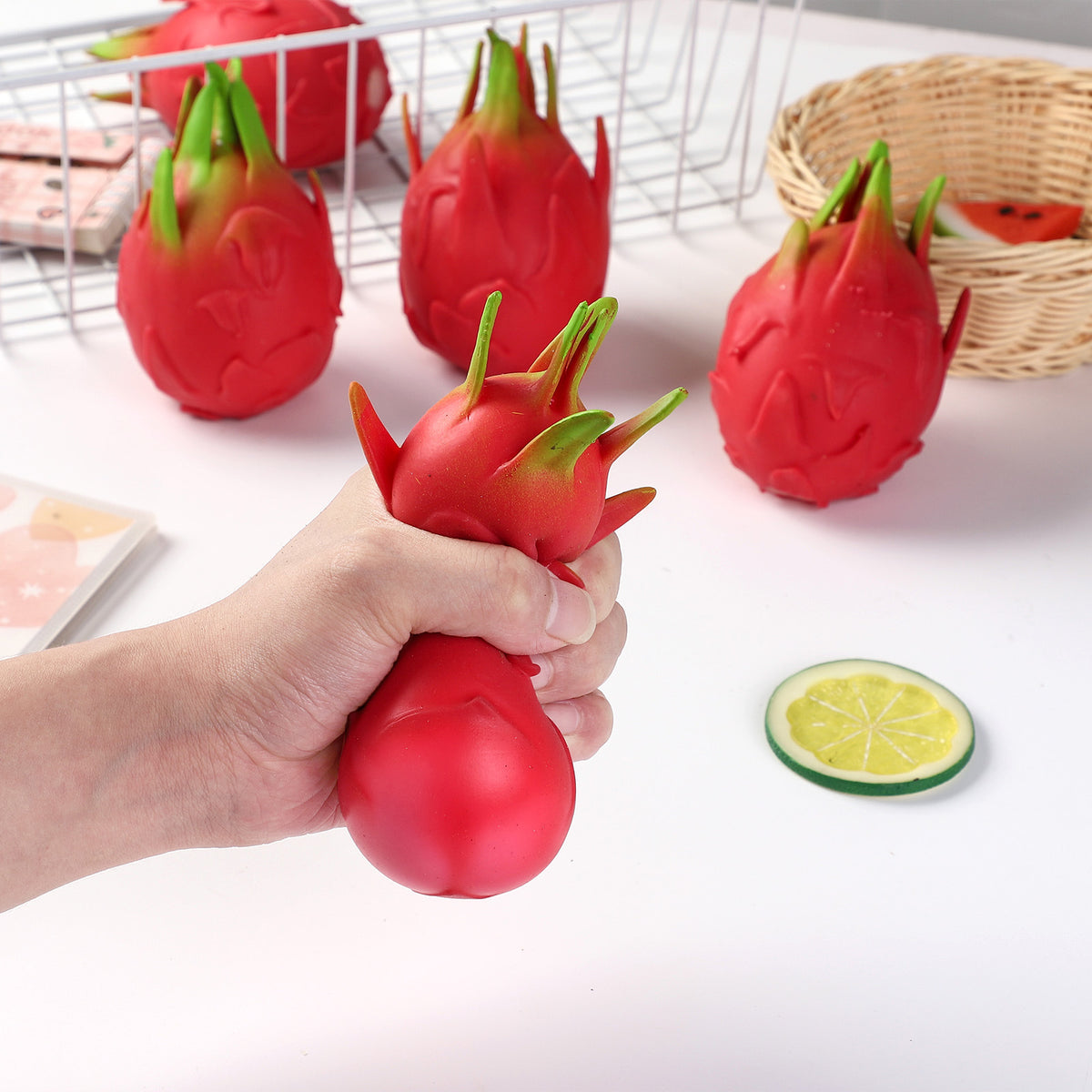 Red dragon fruit stress-relief gag toy with green leafy top, held in hand