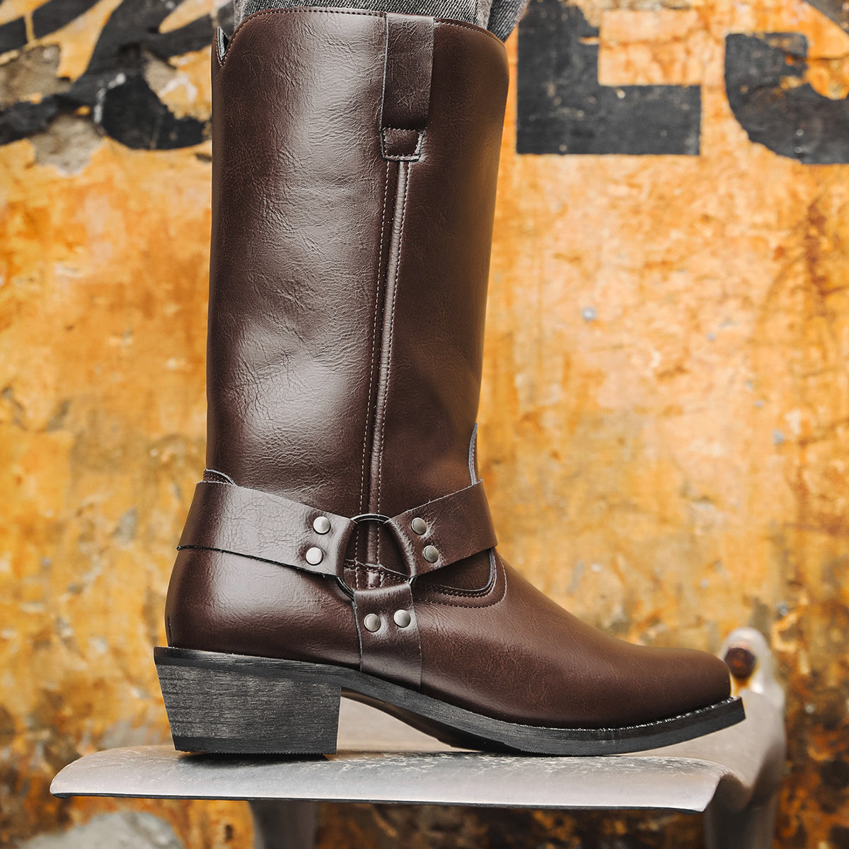 Dark brown cowboy boots, square toe, chunky heel, slip-on shaft with front buckle strap.
