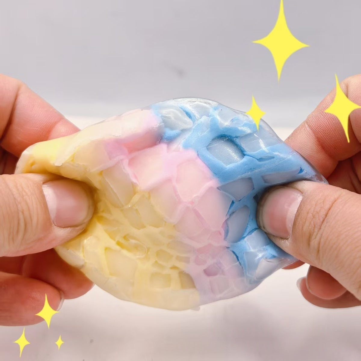 Candy-colored crispy sphere stress-relief squeeze toy with web-like texture, held