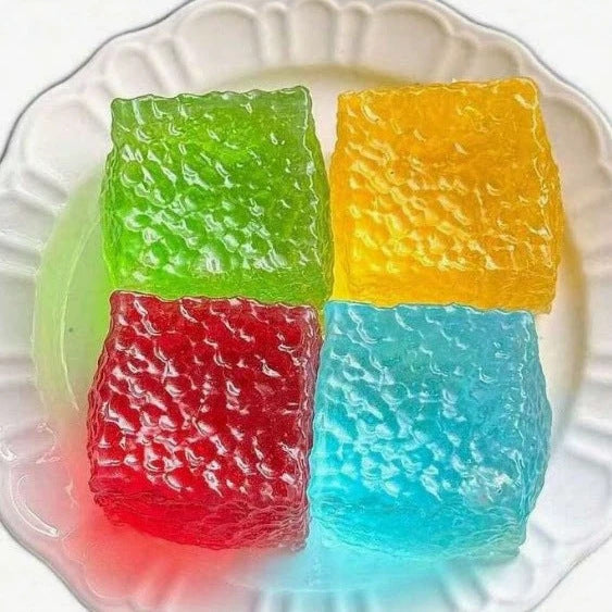 Four translucent squishy cube toys in green, yellow, red, and blue.