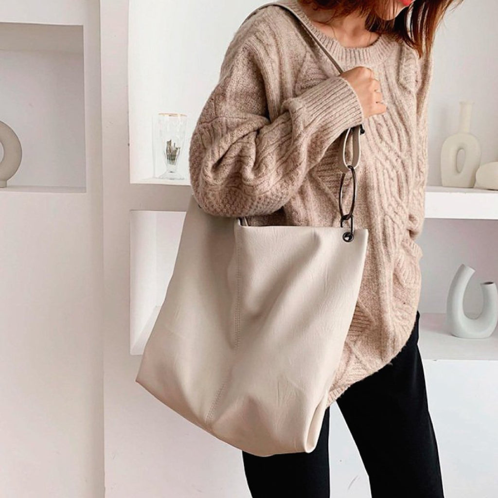 Ivory shoulder bag with wide fabric straps and small ring hardware, slouchy shape