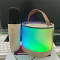 Karaoke speaker with glowing multi-color LED drum and wireless handheld microphone, on desk