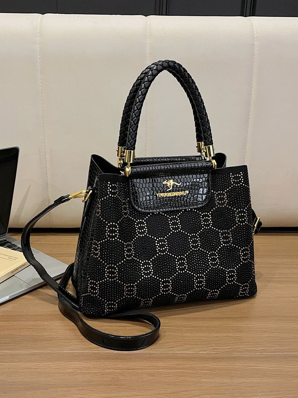 Black structured crossbody bag with embossed pattern, front flap pocket, and top handles