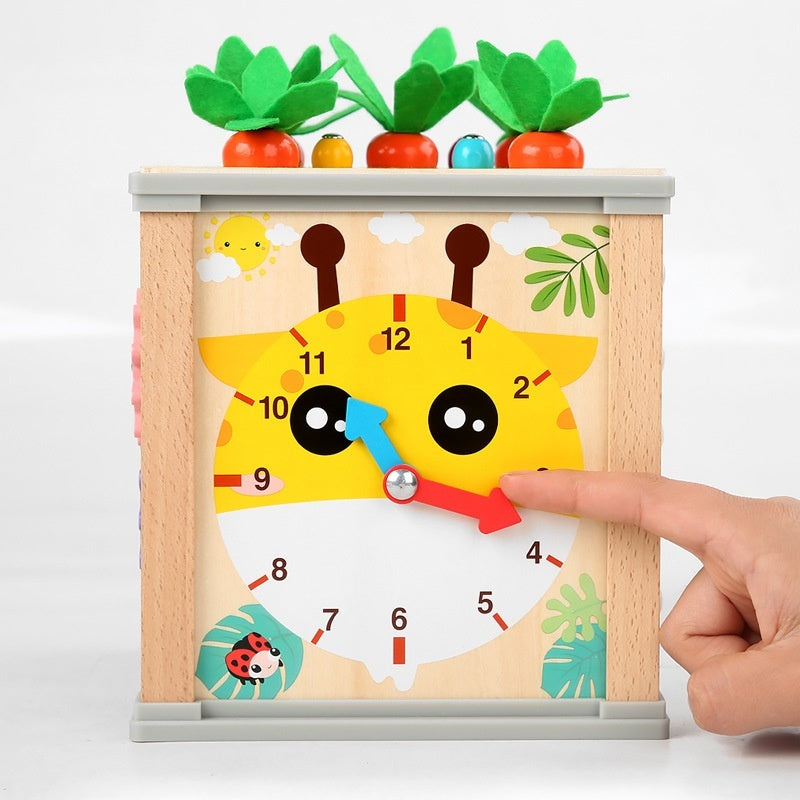 Wooden activity toy clock face with large numbers, hand, and carrot-and-leaf top