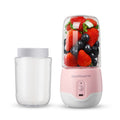 Portable electric juicer cup with clear chamber filled with berries, pink base.