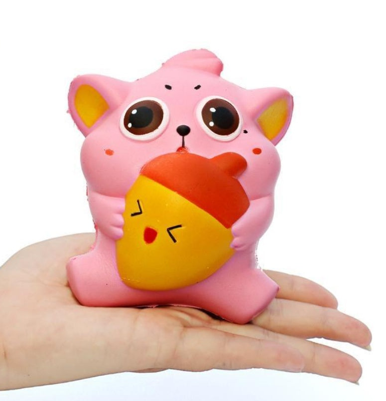 Slow-rising squishy toy pink cat with large eyes holding orange and yellow heart cushion