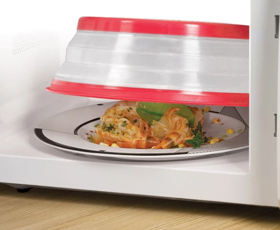 Red collapsible microwave splash cover fitted over food in a microwave