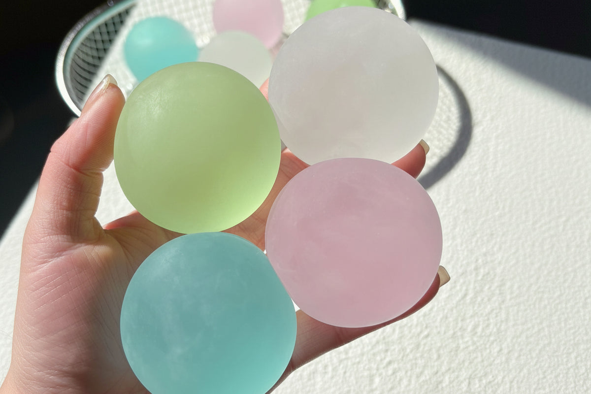 Set of four pastel translucent round squishy candy squeeze toys in green, blue, pink, white