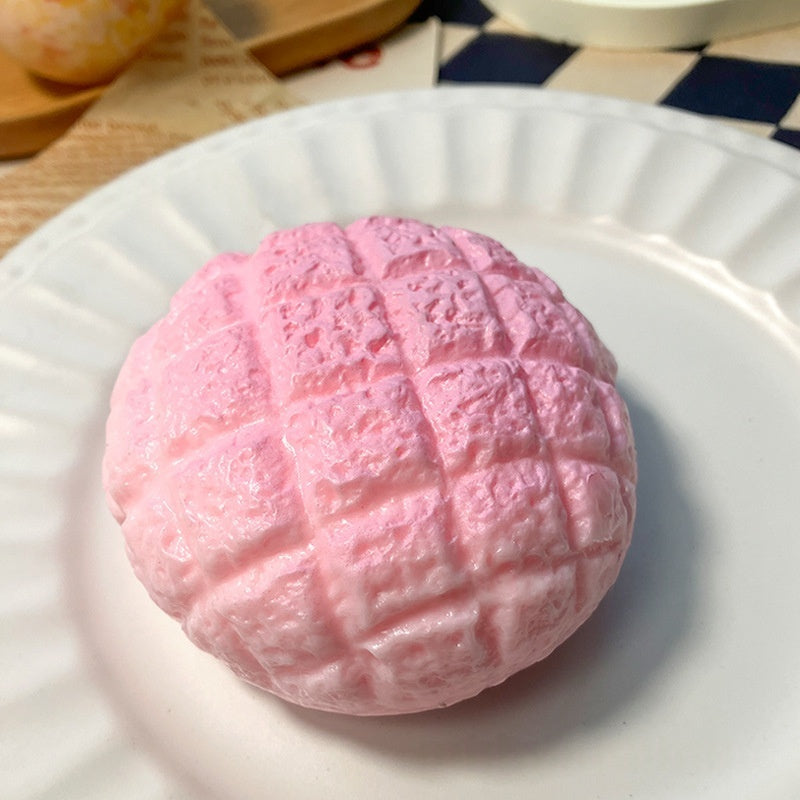 Pink pineapple bun stress relief squishy toy on a white plate, textured