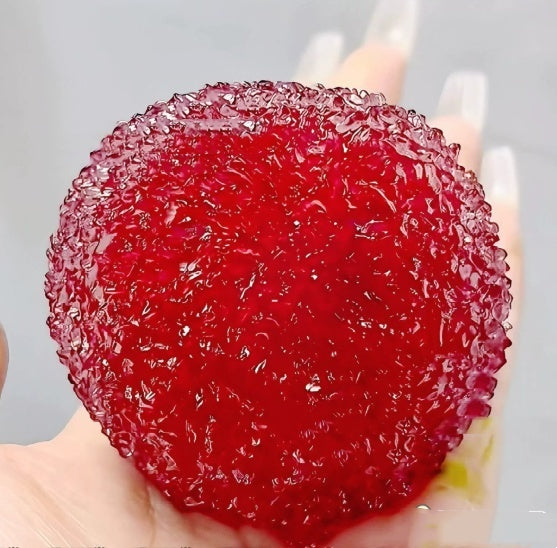 Red textured squishy bayberry stress toy, close-up underside in hand