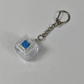 Clear cube stress-relief keychain toy with blue finger-popping button and metal chain