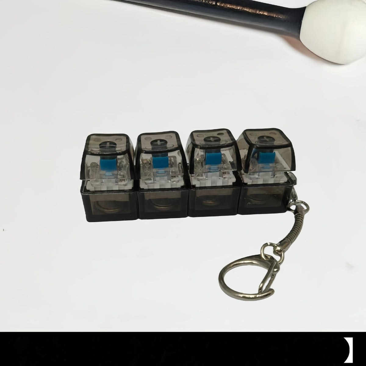 Glowing mini keyboard keycap keychain with transparent black caps and blue-lit switches