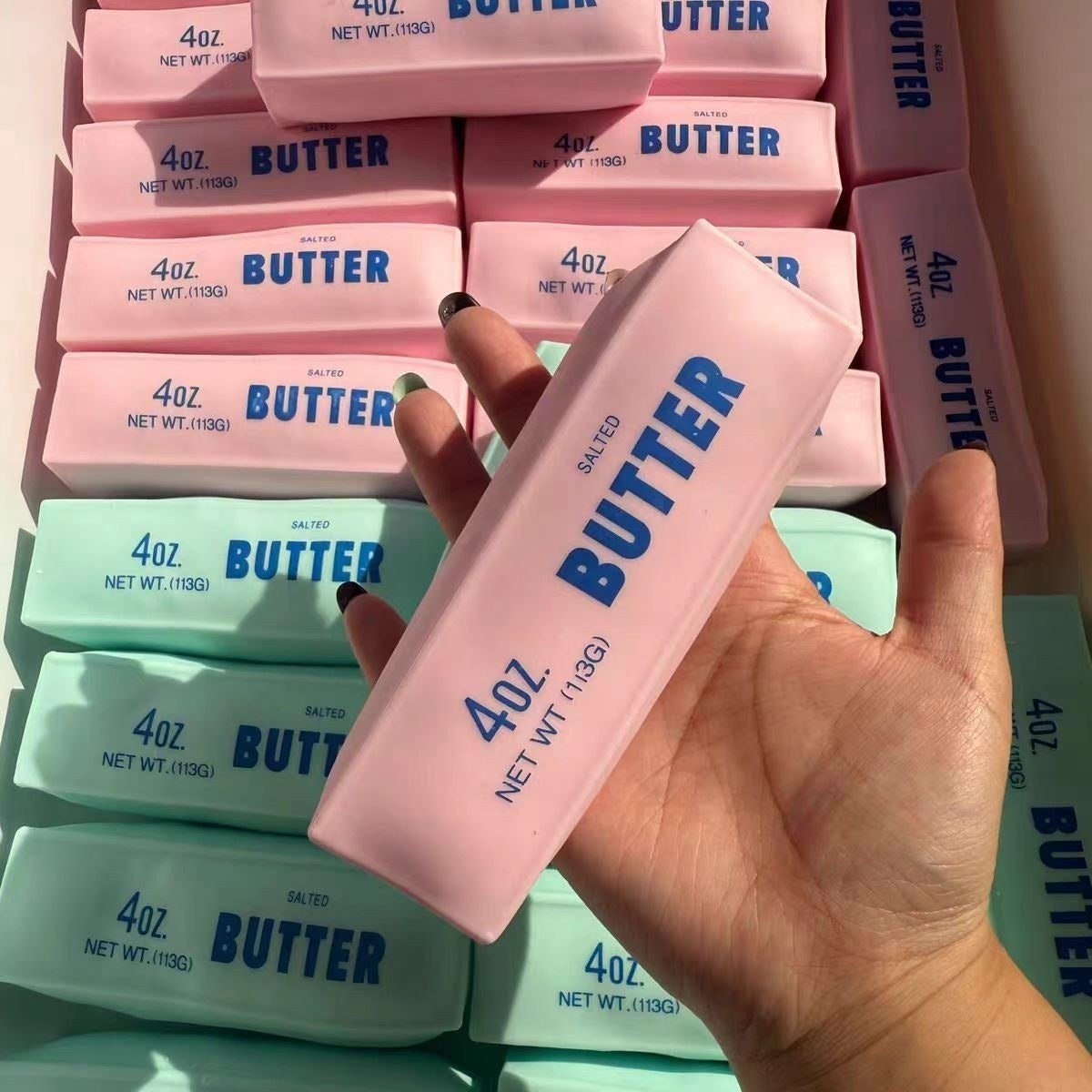 Pink butter-shaped squishy stress-relief toy bar among stacked bars