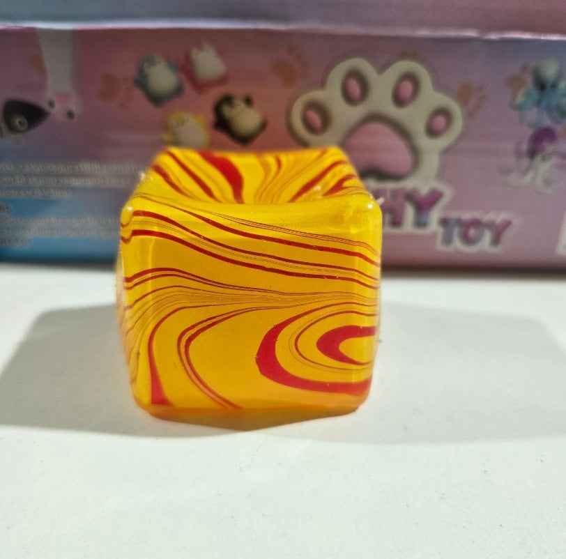 Yellow cube squeeze stress-relief toy with red swirl lines across the surface.