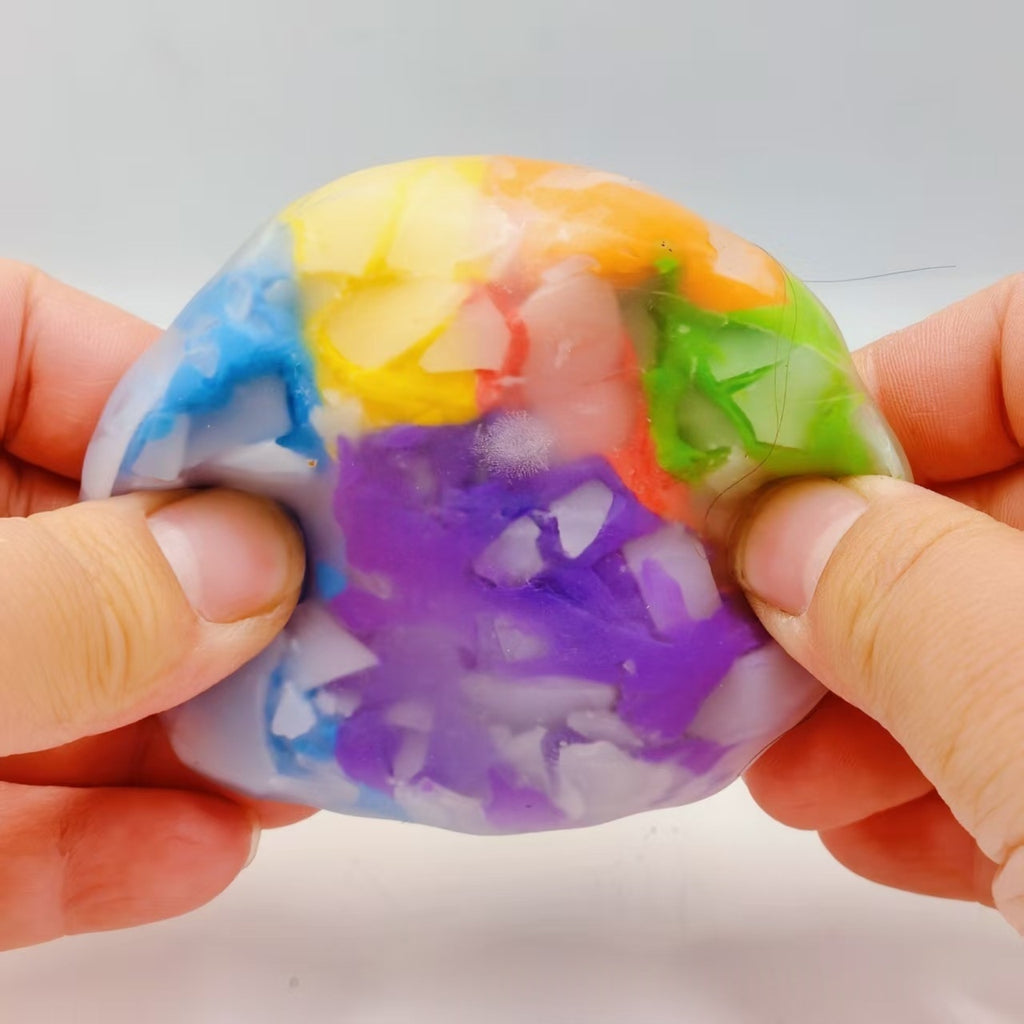 Rainbow-colored crispy sphere stress-relief squeeze toy, held between fingers