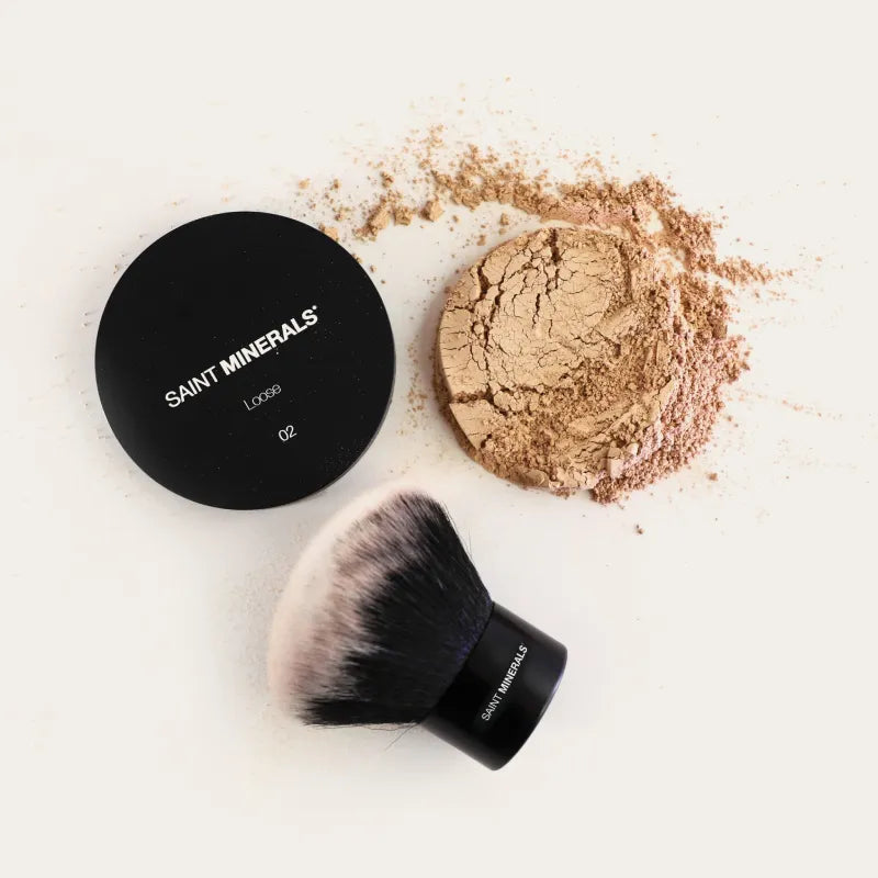 SAINT MINERALS loose powder compact with tan powder and makeup brush, shade visible.