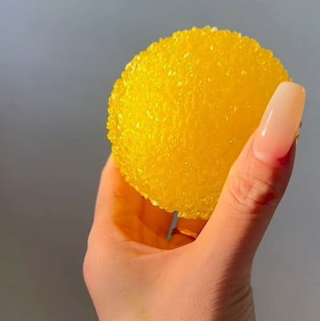 Yellow textured bayberry-shaped squishy stress toy with small stem, in hand