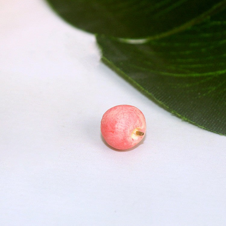 Pink toy fruit piece with small green leaf