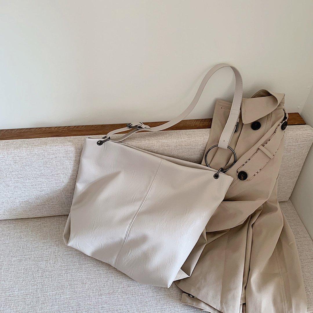 Ivory shoulder bag with adjustable strap, ring hardware, and roomy slouchy body