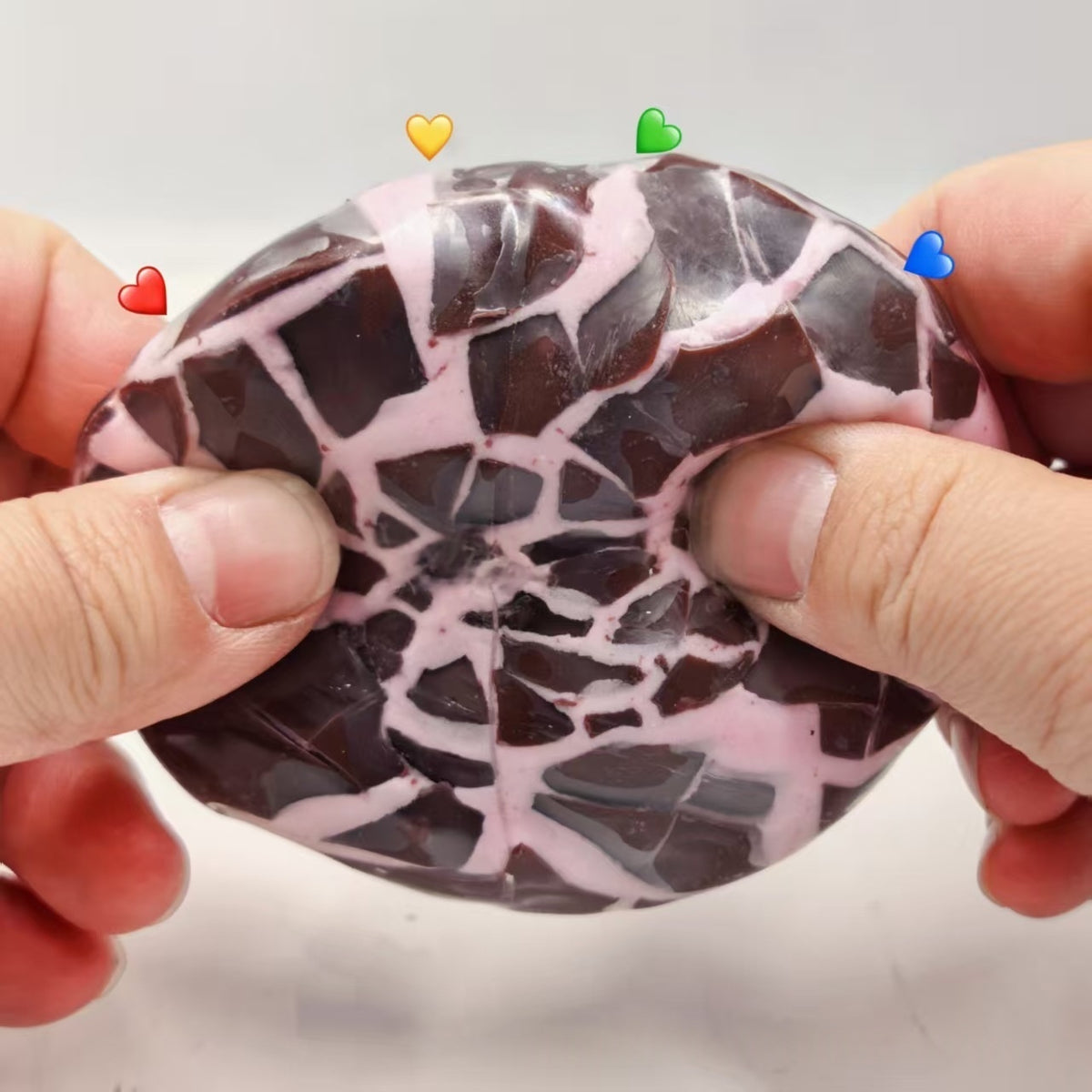 Chocolate-and-white marbled crispy sphere stress-relief squeeze toy, held in hands