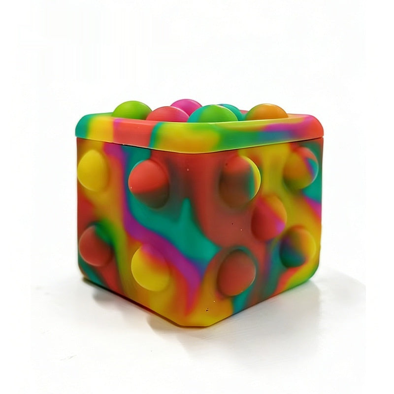 Square silicone bubble stress ball with bright rainbow bumps, resting on a white surface