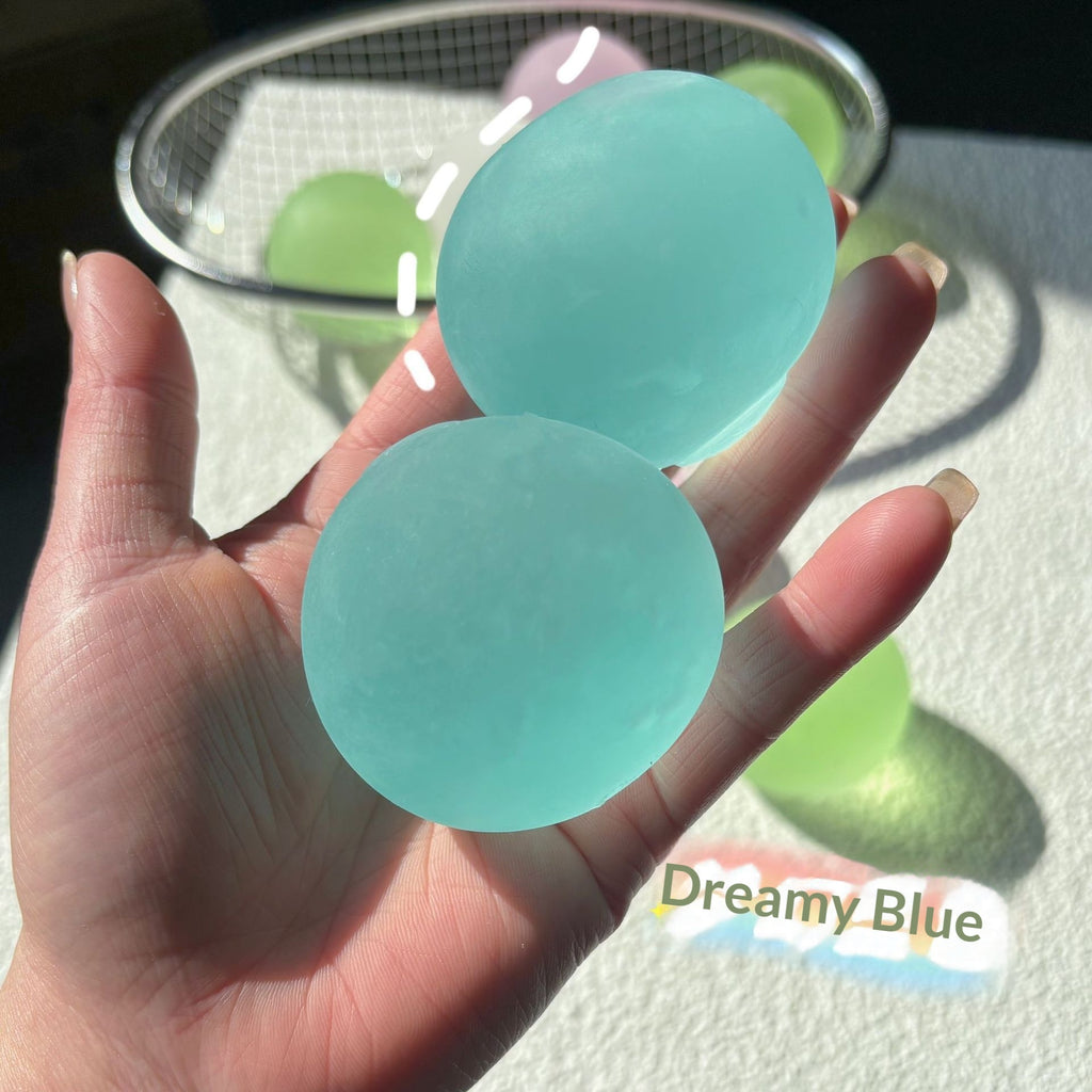 Two pastel translucent round squishy candy squeeze toys, mint blue and green, in hand