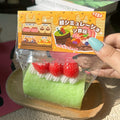 Strawberry swiss roll cake squishy squeeze toy in clear wrapper with red berry topping