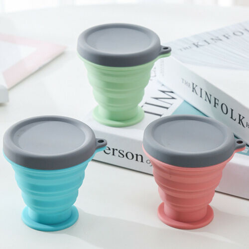 Collapsible silicone travel coffee cup in light green with gray lid and side handle loops