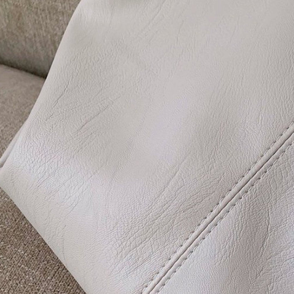 Ivory faux-leather shoulder bag corner with stitched edge and smooth grain texture