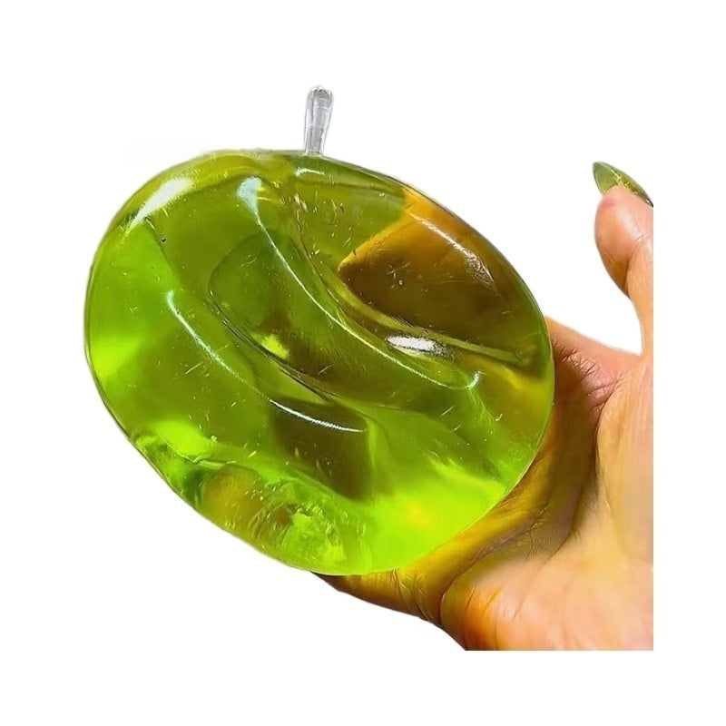 Green translucent apple stress squeeze toy, hand squeezing top view, stem visible