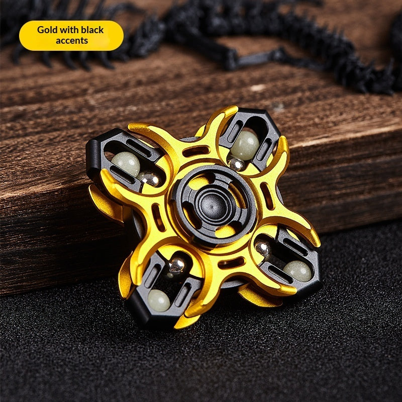 Gold and black fidget spinner with central bearing and four grip sections on wood