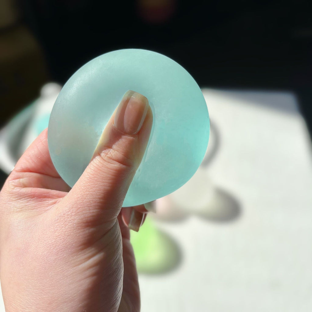 Translucent round squishy candy squeeze toy, light blue, held in hand