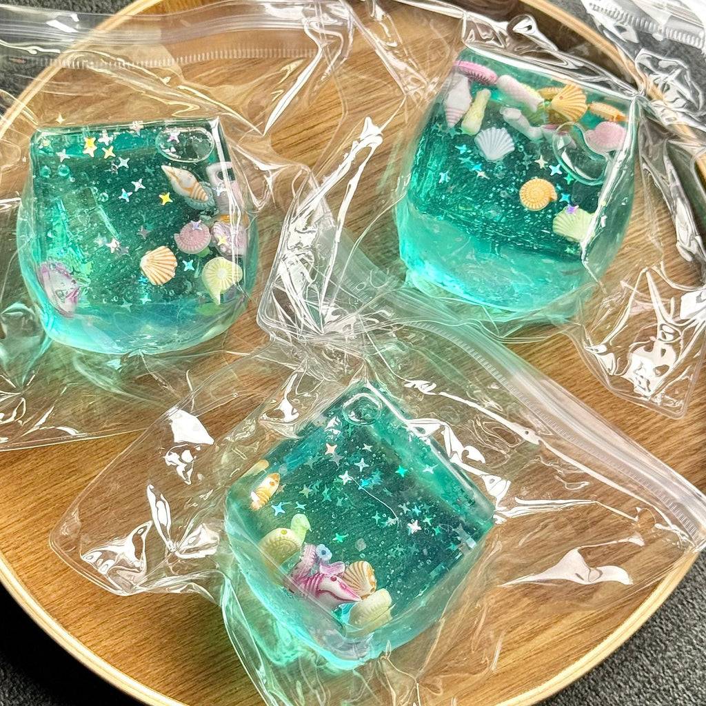 Three aqua blue squeeze cubes in clear bag with seashell and starfish icons