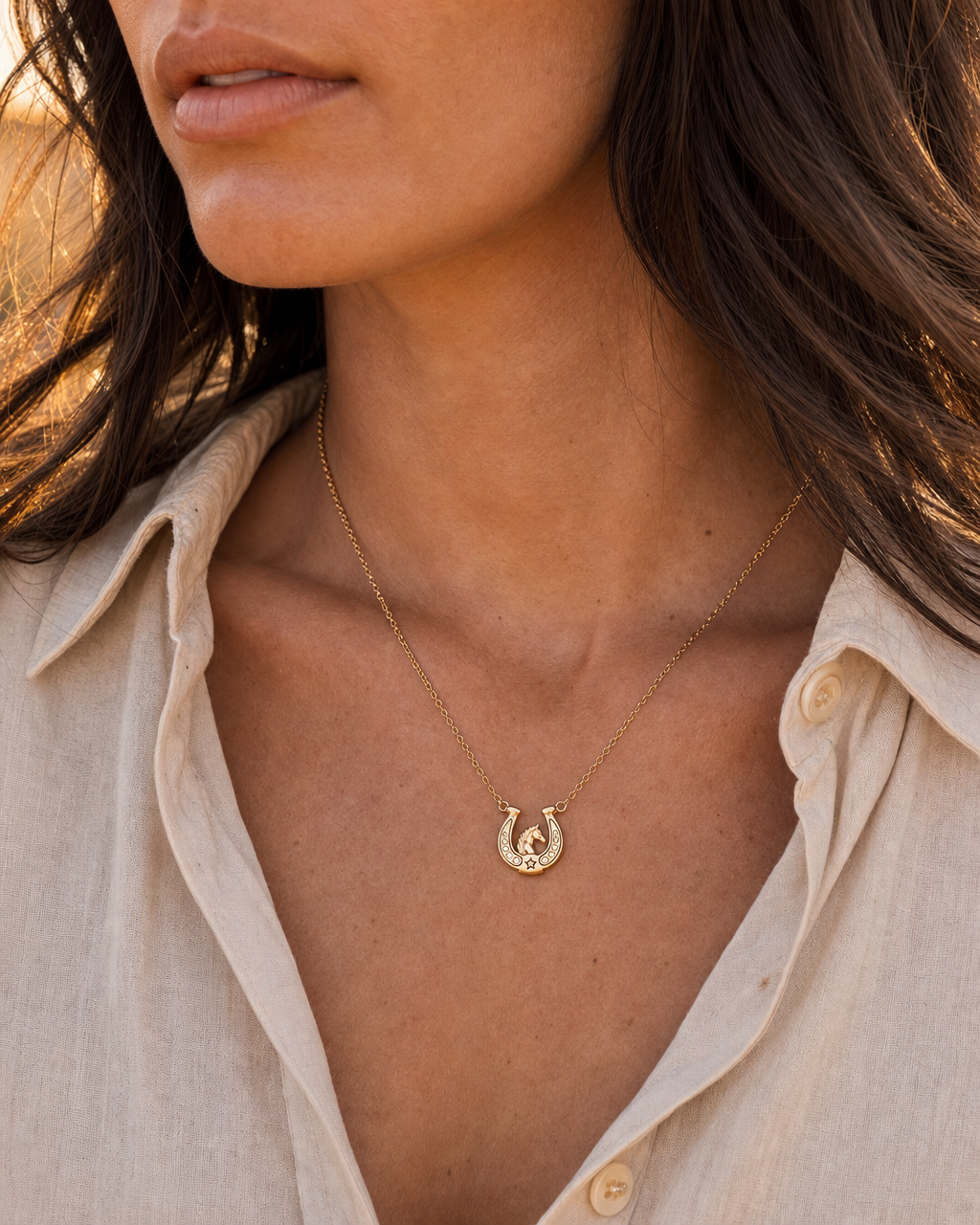 Gold horseshoe pendant necklace on model with small horseshoe charm at chest