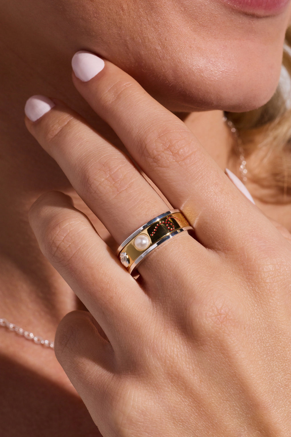 Two-tone baseball fidget ring worn on finger, featuring baseball emblem and pearl accents