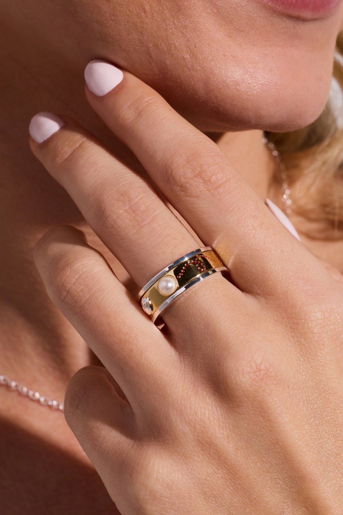 Two-tone baseball fidget ring worn on finger, featuring baseball emblem and pearl accents